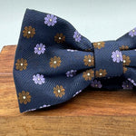 <ul> <li>Cruciani &amp; Bella Bow Tie</li> <li>100% Woven Silk Jacquard Made in England</li> <li>Handmade in Italy</li> <li>Navy Blue, Brown and Light Violet motif</li> <li>Handcrafted in Italy</li> <li>Coated metal Labels</li> <li>Bow Ties</li> </ul>