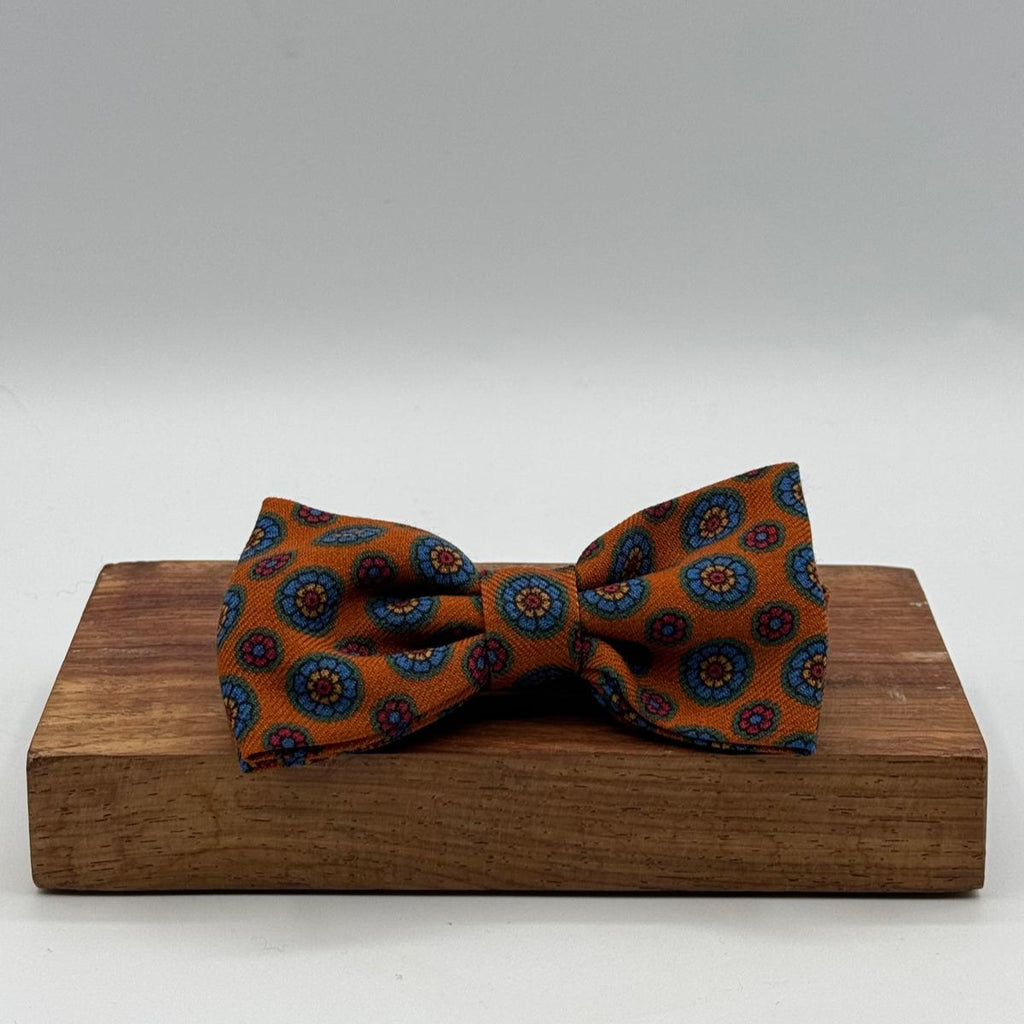 Cruciani &amp; Bella Bow Tie
85% Silk and 15 % Wool Made in England
Handmade in Italy
Rust, Red, Orange, Light Blue and Yellow motif
Coated metal Labels
Bow Ties