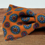 Cruciani &amp; Bella Bow Tie
85% Silk and 15 % Wool Made in England
Handmade in Italy
Rust, Red, Orange, Light Blue and Yellow motif
Coated metal Labels
Bow Ties